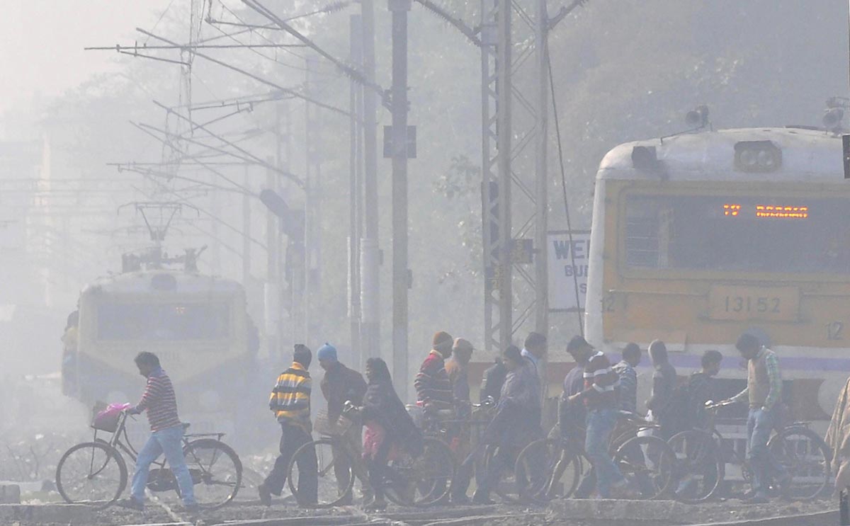 KOLKATA: People cross a railway track as a train arrives through dense fog  on a cold, winter morning in Kolkata on early Monday.(PTI) - The Shillong  Times