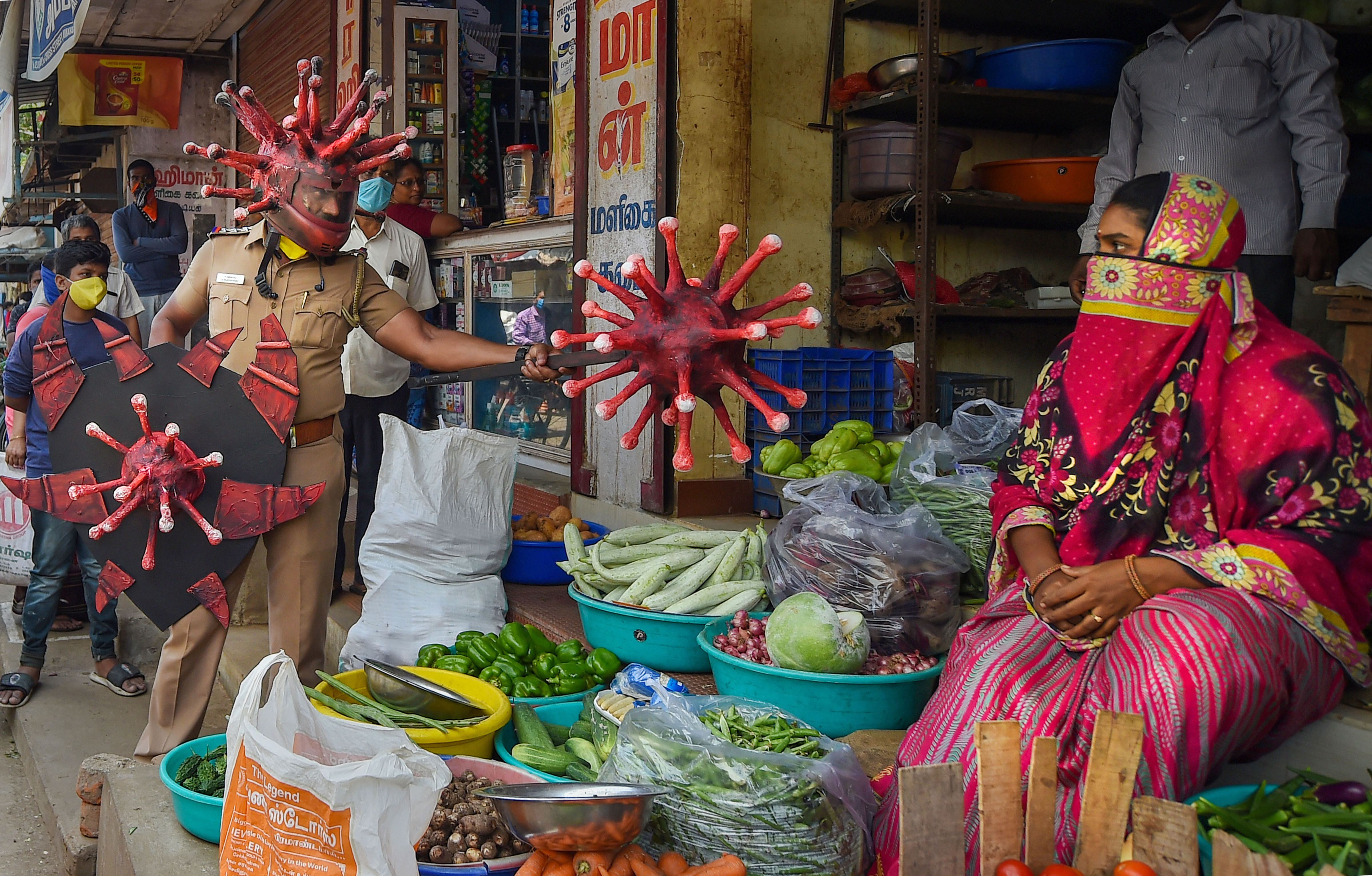 A policeman wearing a coronavirus-themed outfit walks at a market to raise awareness