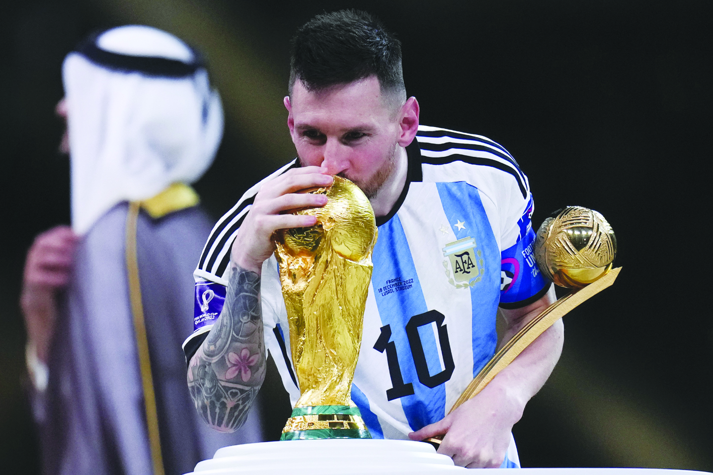 Lionel Messi kisses the FIFA World Cup trophy as he holds the Golden