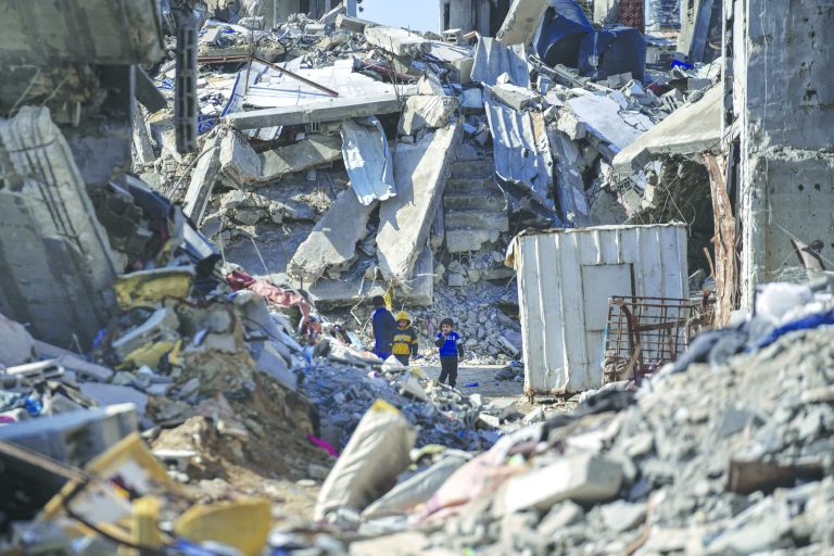 Palestinian children walk amid the rubble of homes, destroyed by the Israeli army’s air and ground offensive against Hamas in Bureij refugee camp, central Gaza Strip, on Monday. (PTI)